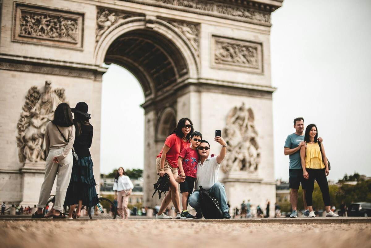 foto de una familia abrazada tomándose una foto tipo selfie con el arco del triunfo detrás.