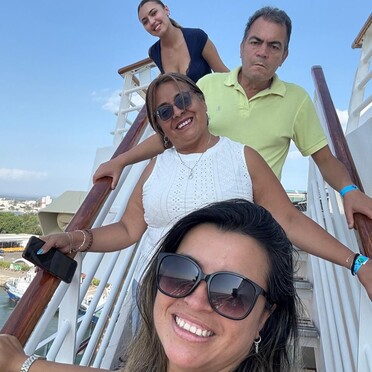 una foto de una familia durante unas vacaciones en crucero por el caribe. son clientes de la agencia de viaje g-travel. foto compartida por Viviana Rivera Jimenez. 2026. están en la barandilla de las escaleras del crucero.