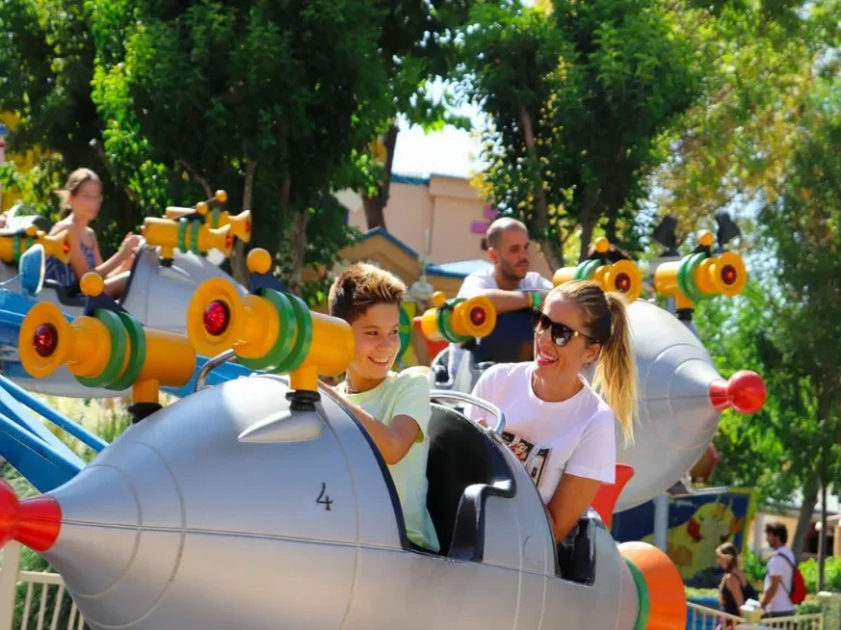 Un hijo y su madre disfrutando de una atracción infantil en forma de cohete en el Parque Warner Madrid de España.