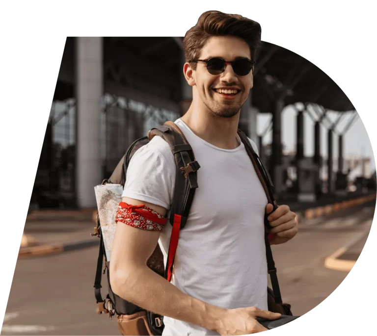 Hombre con maleta de viaje sonrriente, mirando a cámara, usando gafas de sol. La foto está recortada con la forma del simbolo interno del logo de G-travel. Imagen para representar la página de contacto.