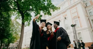 Una foto de unos estudiantes graduados con sus togas y birretes, posando para una selfie.