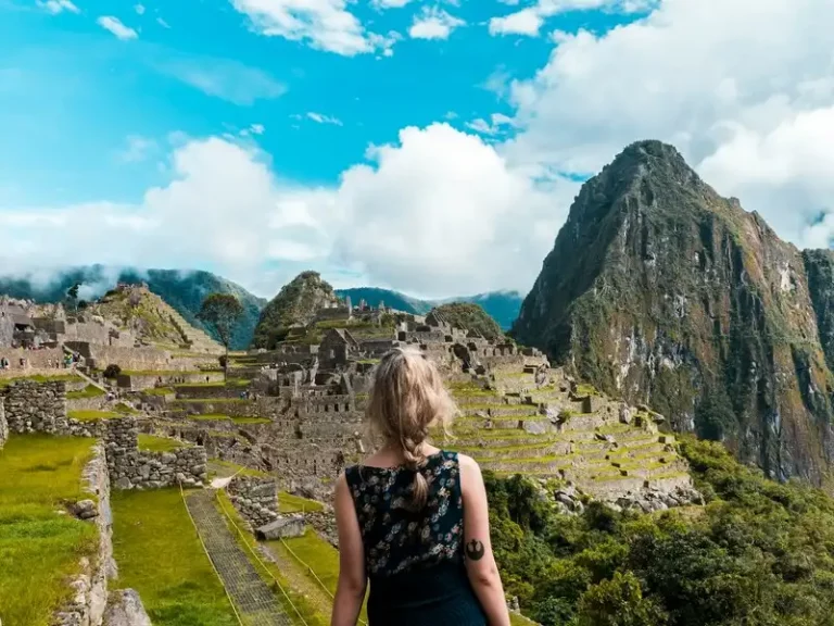 Mujer admirando la vista de Machu Picchu, el sitio arqueológico más icónico del Perú.